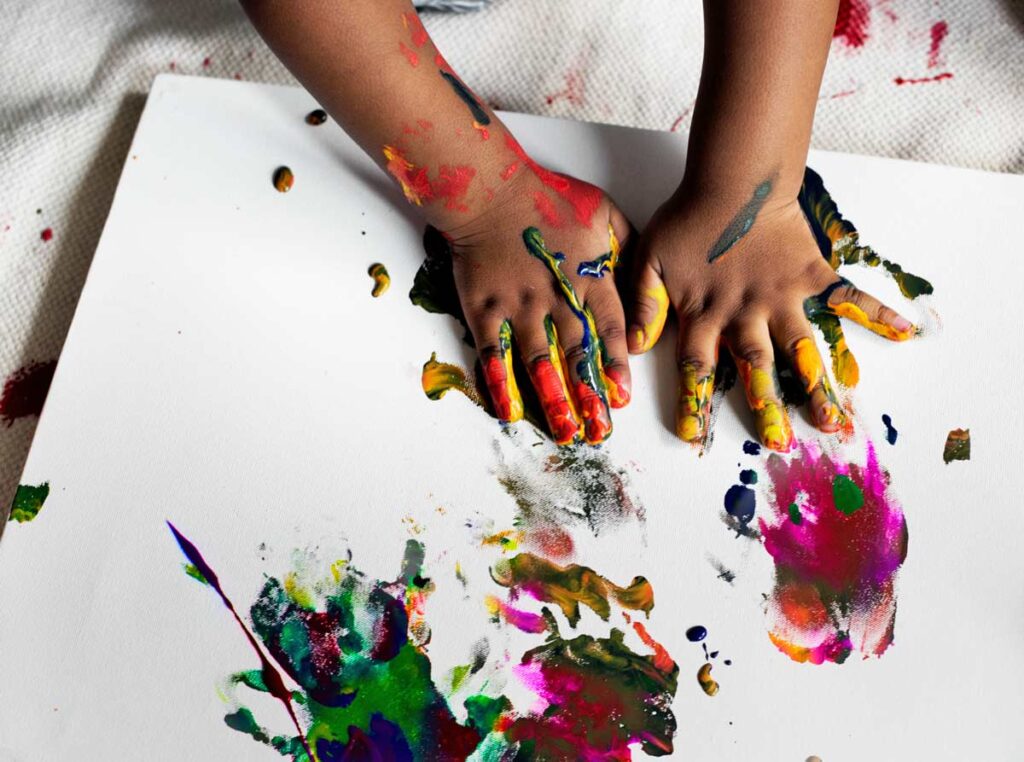 Dziecko maluje farbami przy użyciu rąk